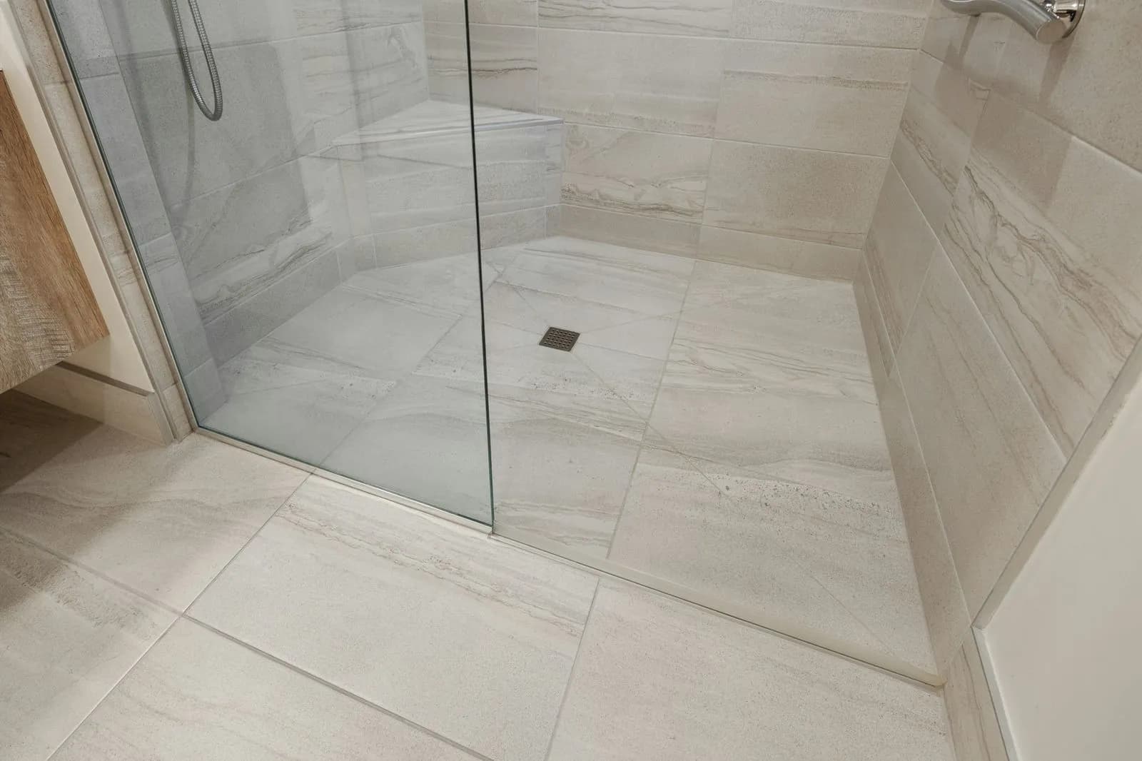 Ducha de obra con porcelánico claro y mampara de vidrio