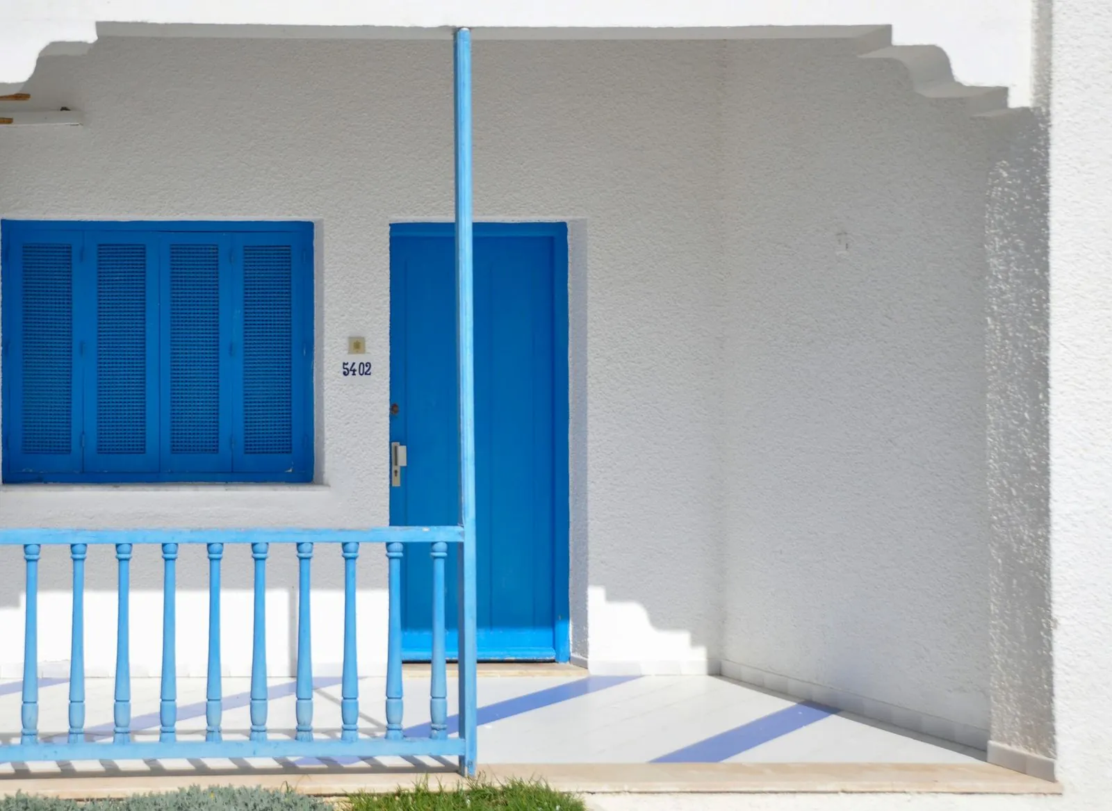 Fachada encalada con puerta y contraventanas azules